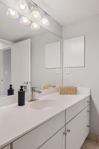 Bright vanity area offers generous counter space, abundant storage, updated fixtures, and an expansive mirror.