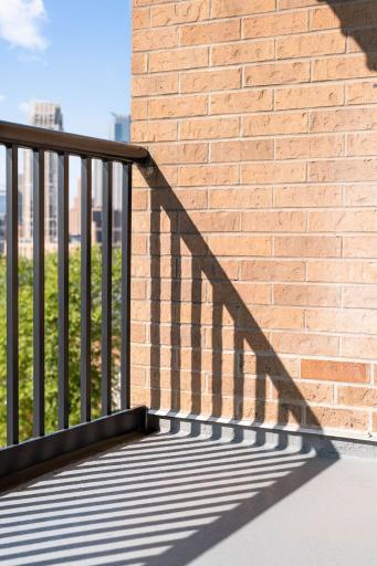A sunny balcony corner offers a private spot to enjoy fresh air with the Downtown Minneapolis skyline just beyond.