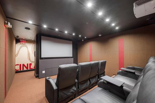 Movie theater amenity with theater-style recliner seating and large screen.