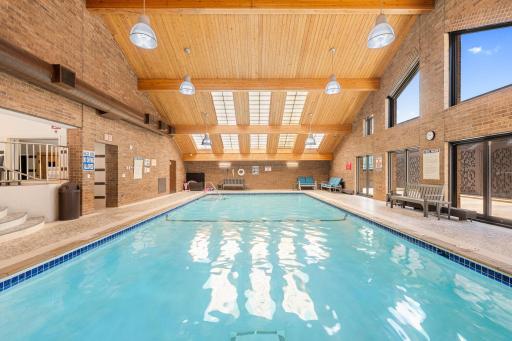Indoor pool with vaulted wood ceiling, skylights, and lounge seating.