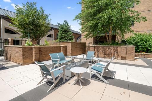 Outdoor patio seating area with fire feature and landscaped surroundings.