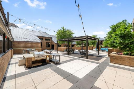 Outdoor patio with grilling station, pergola, string lights, and multiple seating areas.