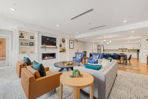 Newly remodeled community room with lounge seating, fireplace, dining area, and full kitchen.