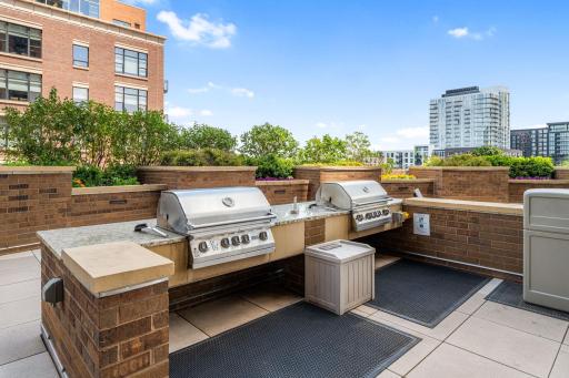 Outdoor grilling area with built-in grills, countertops, and landscaped surroundings.