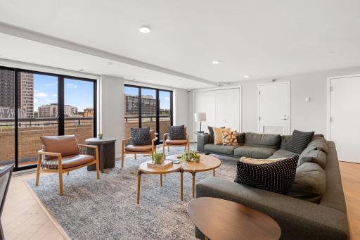 Comfortable community lounge with large windows and access to outdoor patio space.