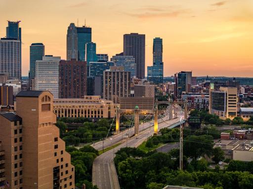 Golden-hour views showcase the downtown skyline and iconic Hennepin Avenue Bridge illuminated against the evening sky.