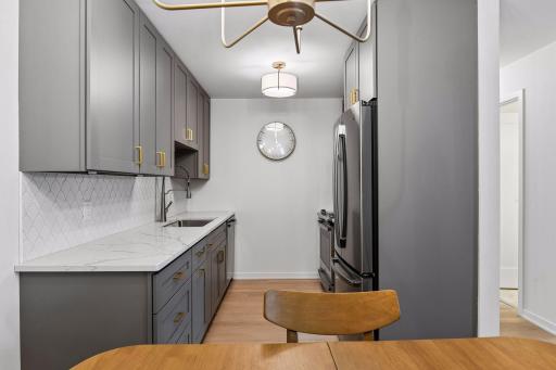 The completely updated kitchen features new cabinetry, quartz countertops, and a stylish tile backsplash.