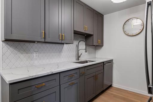 The completely updated kitchen features new cabinetry, quartz countertops, and a stylish tile backsplash.