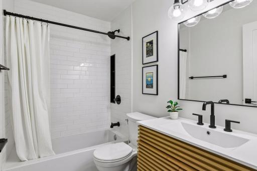 The beautifully updated bathroom feels fresh with white subway tile, a new vanity, and stylish finishes throughout.