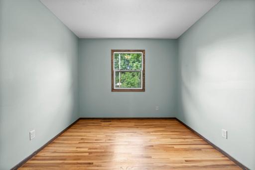 Third main-level bedroom with hardwood floors & backyard views