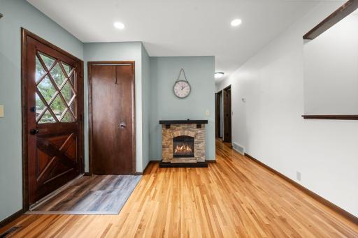 Bright foyer with coat closet, hardwood floors & cozy electric fireplace