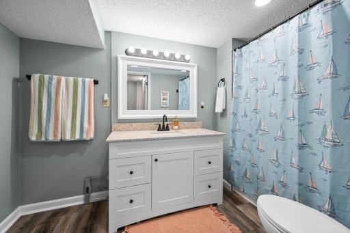 Updated lower-level full bath with subway-tiled tub surround
