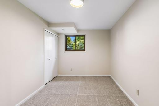 One of two versatile lower-level bedrooms/flex spaces, both featuring newly installed flat, drywalled ceilings in place of the original drop ceilings. Ideal for a home office, hobby room or additional living space.