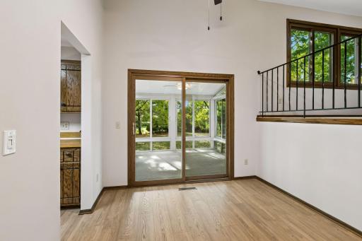 Perfectly framed like a photograph, the sliding glass doors offer a beautiful view of the three-season porch and wooded backyard beyond, bringing the outdoors into the dining space.