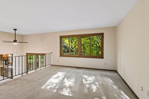 The spacious upper-level living room features large windows overlooking the wooded surroundings.