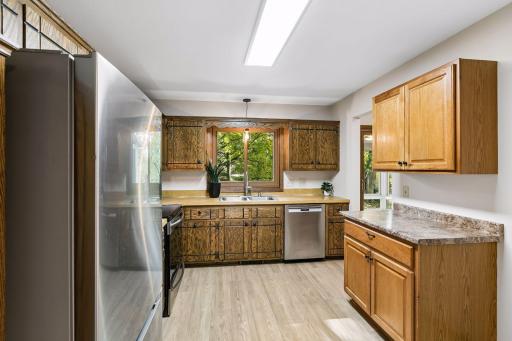 Warm cabinetry provides generous storage and counter space, complemented by stainless steel appliances. Enjoy beautiful backyard views while preparing meals or cleaning up at the double-basin sink.