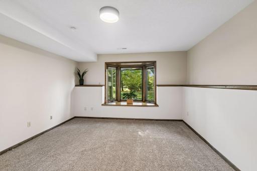 The lower-level family room features a charming bay window with built-in blinds, offering beautiful views of the wooded backyard. A comfortable and inviting space with plenty of room to relax, entertain or gather with family and friends.