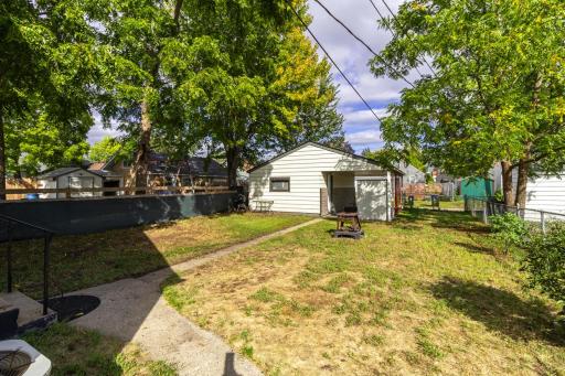 Fenced yard with 1 car garage with a car port