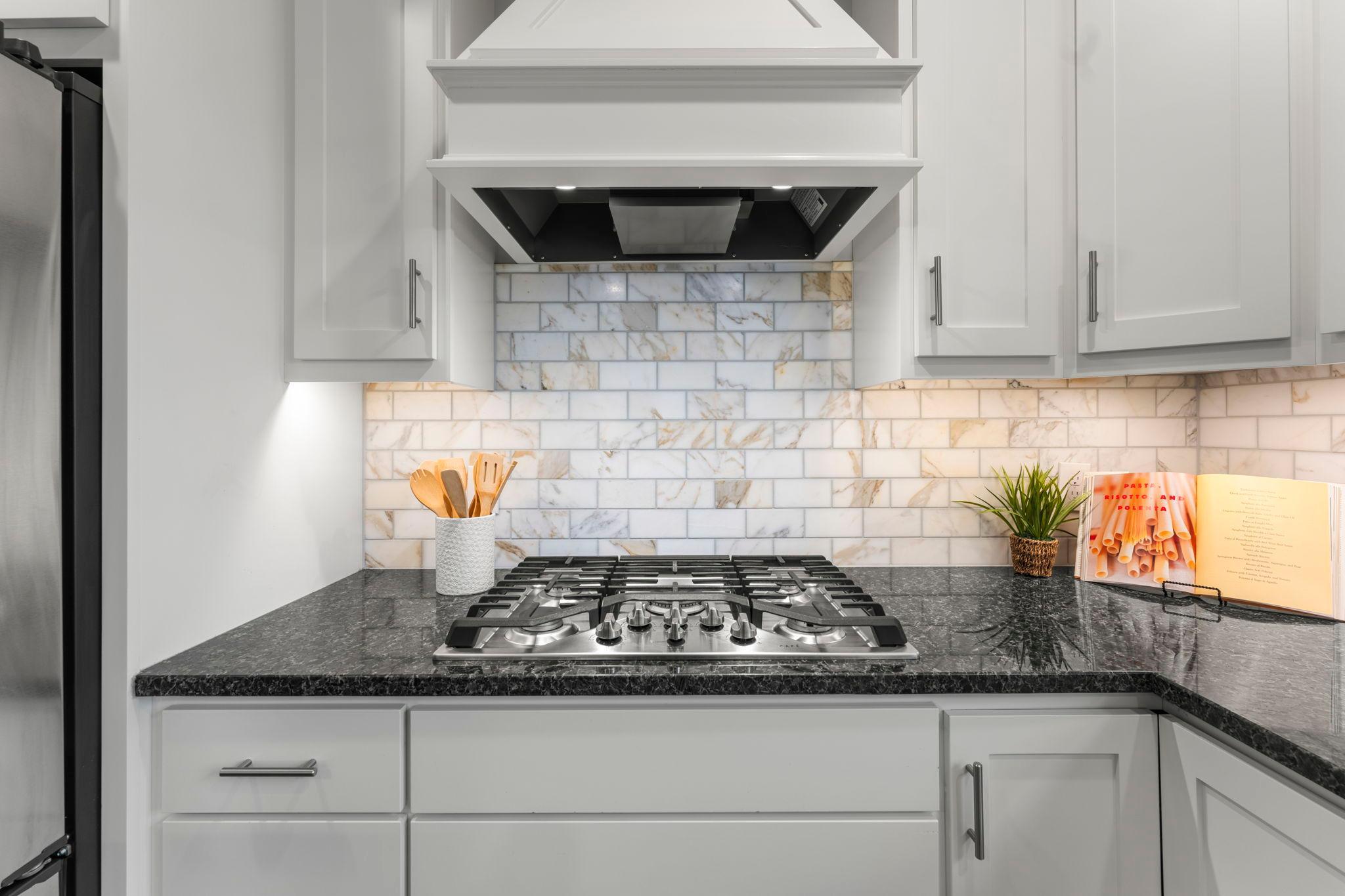Enjoy preparing your meal using the 5-burner stove with a hooded vent. The tile backsplash adds a beautiful decorative touch.