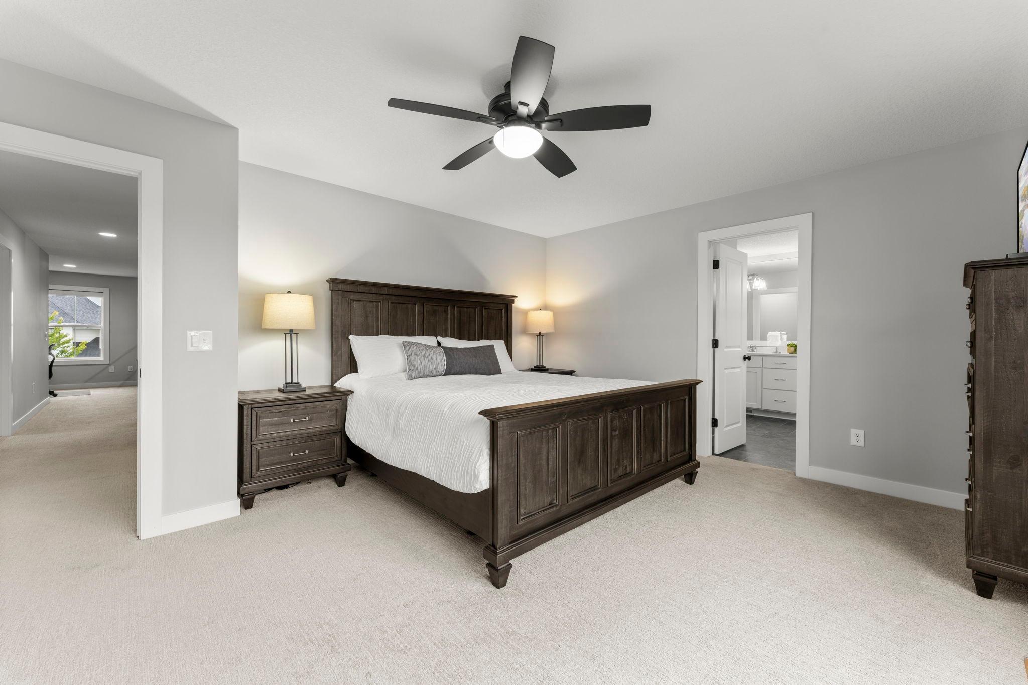 The spacious primary bedroom features a private full primary bathroom, a ceiling fan, and a wall of windows that fill the room with natural light.