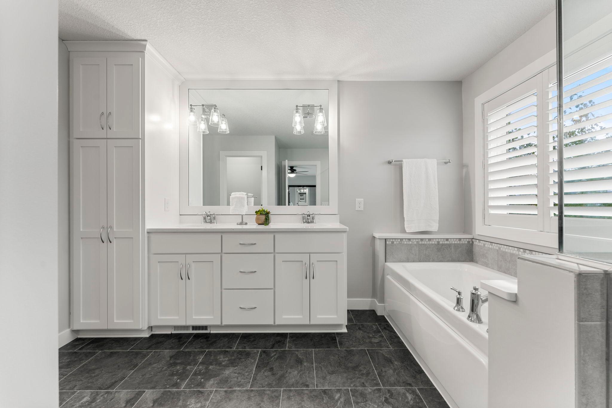 The private primary bathroom has a spa-like feel. It features a glass walk-in shower, soaking tub, comfort-height double vanity with storage, a ceramic tile floor & a large linen closet.