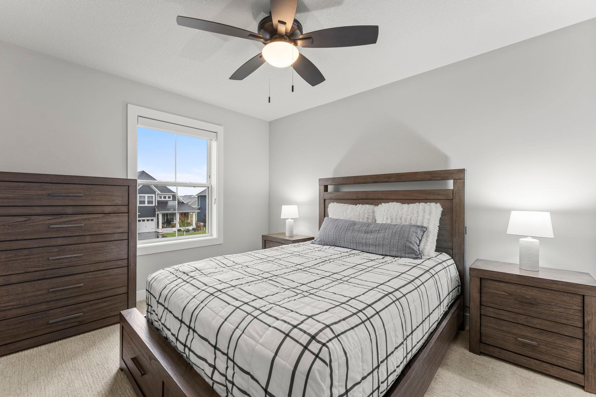 Bedroom two on the upper level features a ceiling fan, a large window, and a spacious closet with French doors.