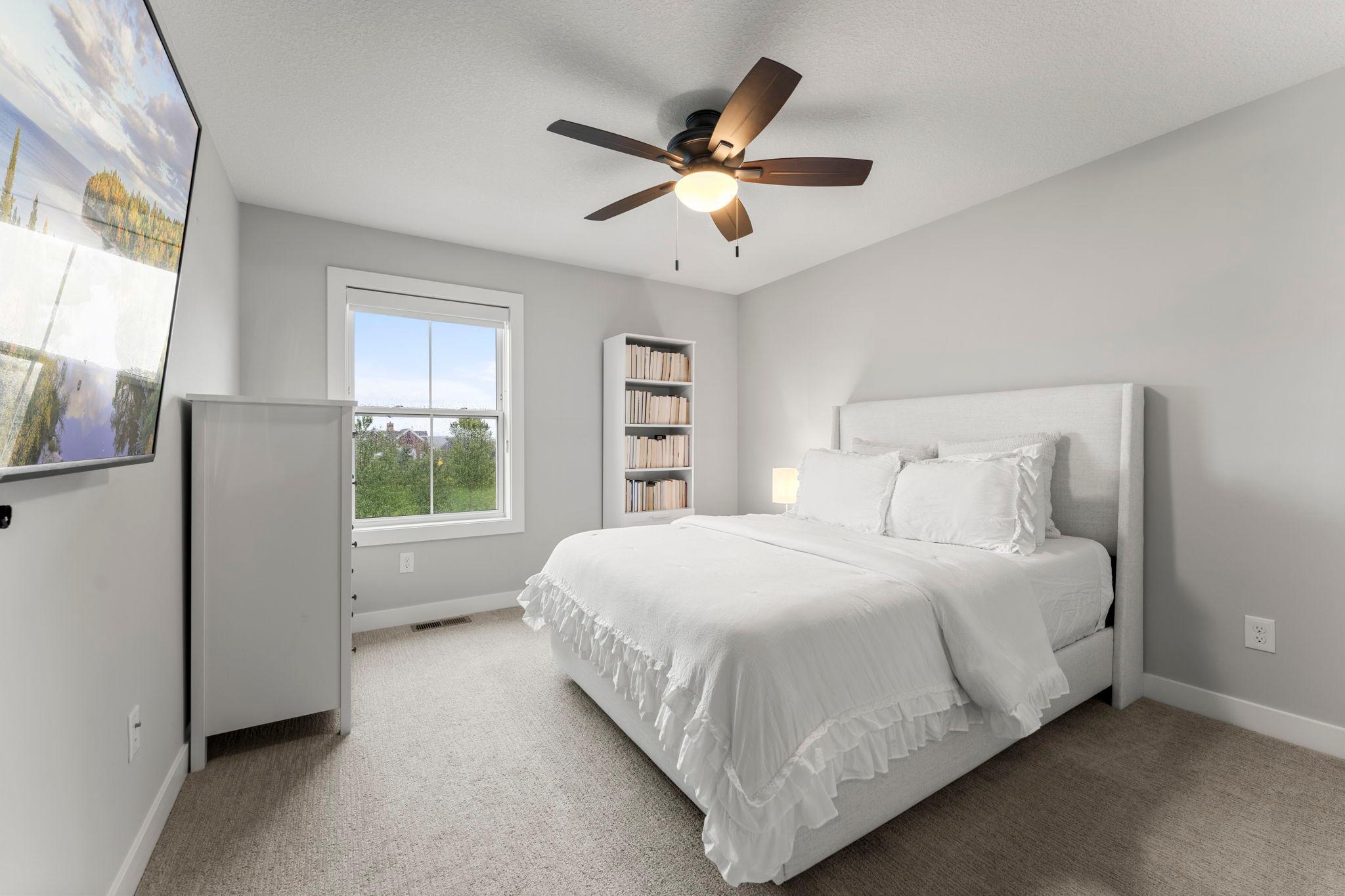 The fourth bedroom on the upper level includes a large window, a ceiling fan and a spacious closet with French doors.