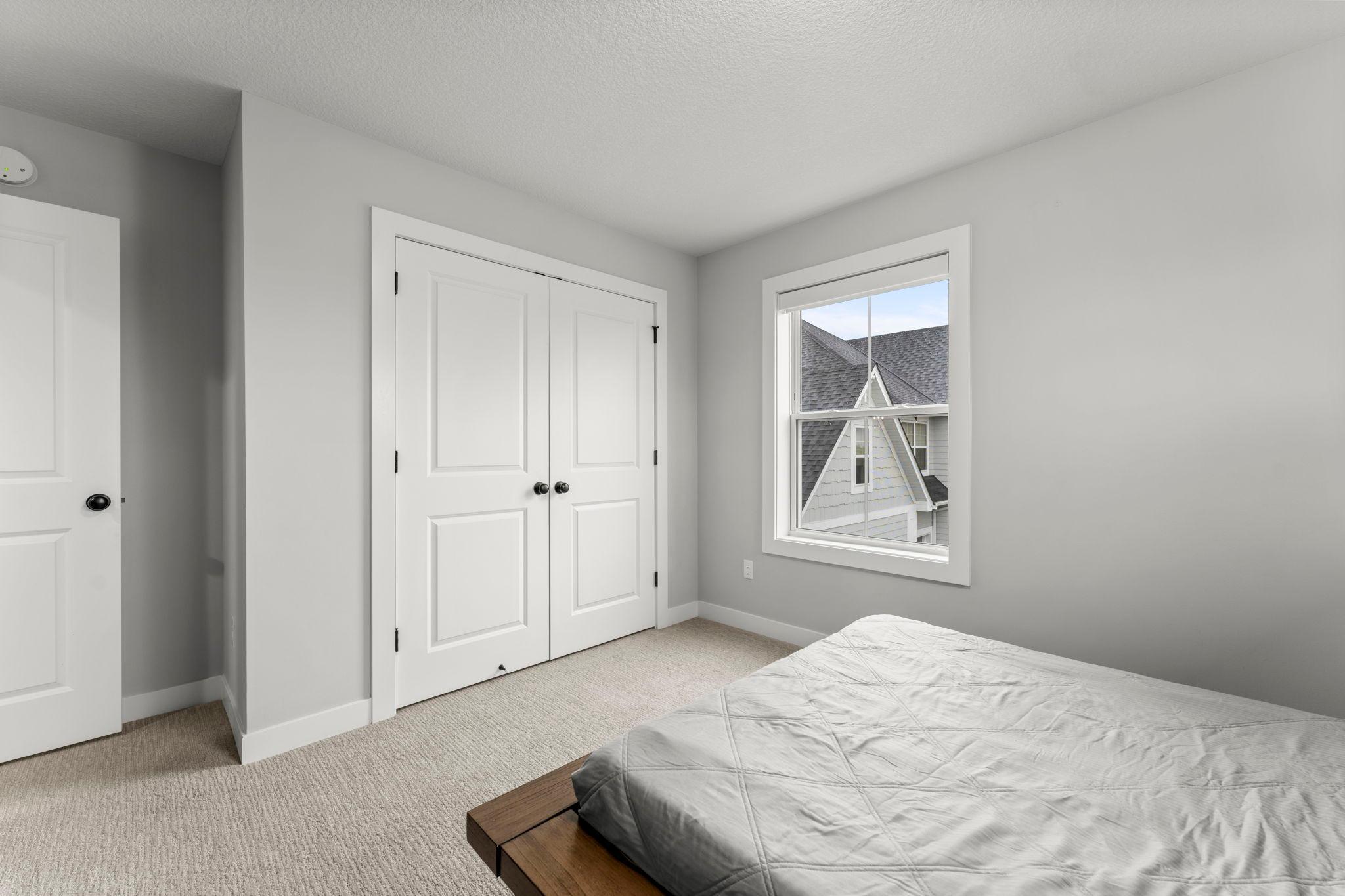 Another view of bedroom three highlighting the large closet with French doors.