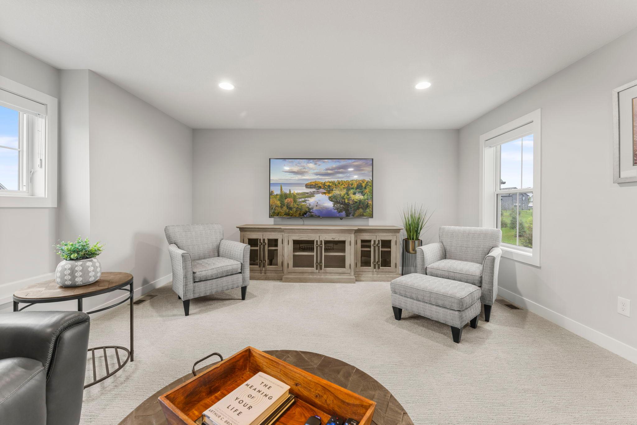 A different view of the family room showing two windows and recessed lights that brighten the space.