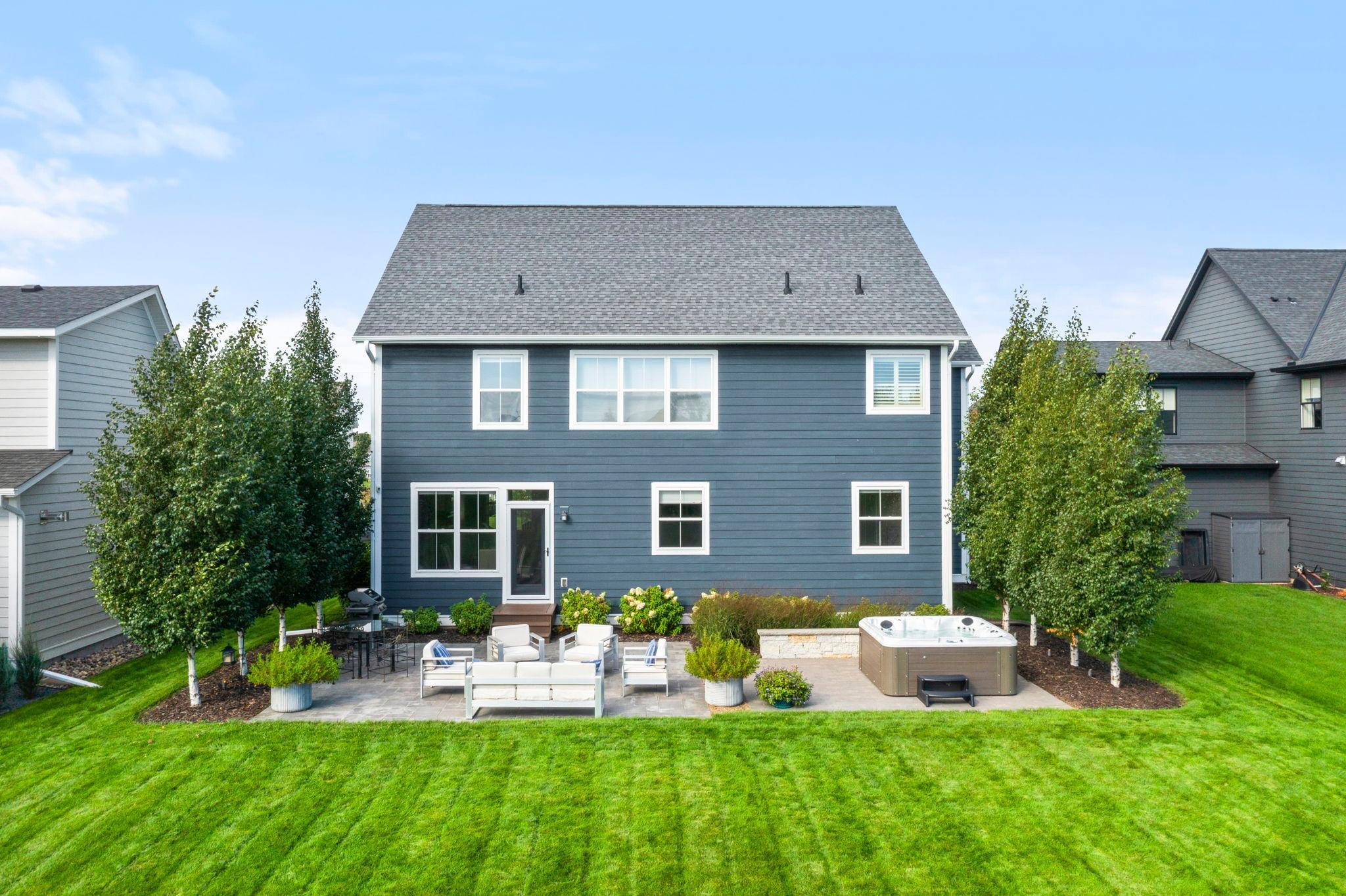 Mature trees flank the backyard patio and hot tub, providing privacy.