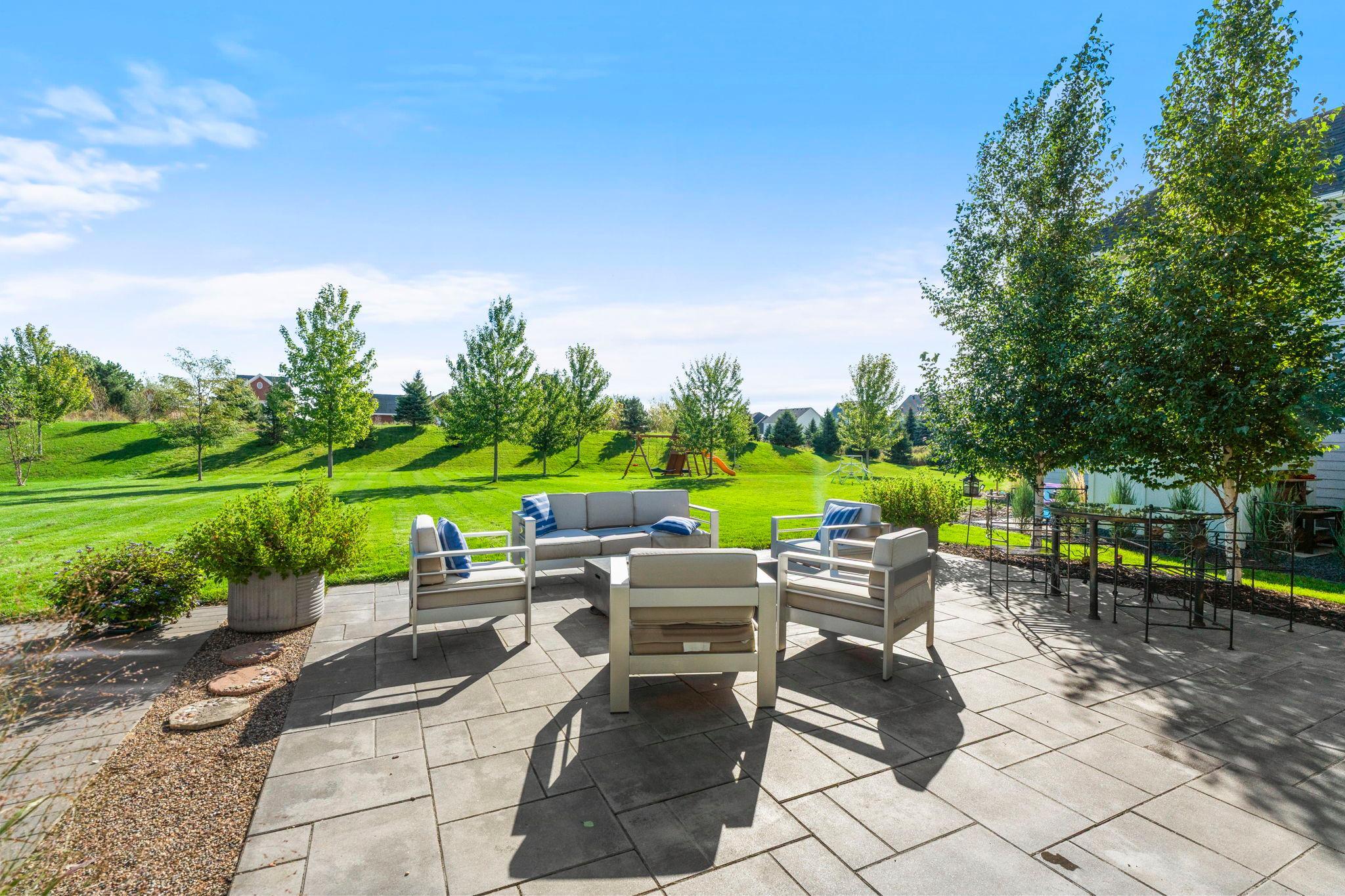 The backyard extends the living space outdoors with a large paver patio, mature landscaping, a flat lawn, and room to settle in for long summer evenings.