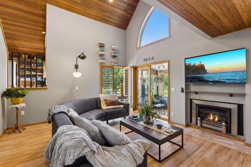 A second view highlights the impressive ceiling height, distinctive architectural angles, abundant natural light, and seamless connection to the bright three-season porch.