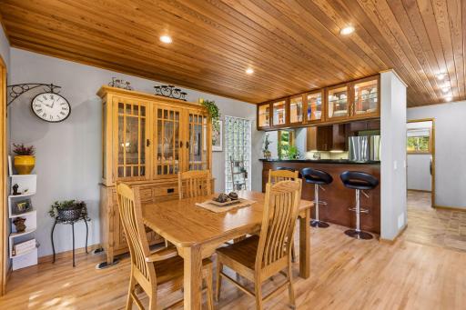 The dining area features a warm wood ceiling, custom built-in cabinetry, and a convenient breakfast bar that connects effortlessly to the kitchen.