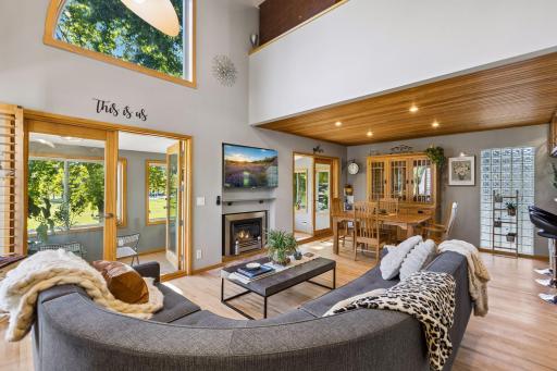The dramatic great room showcases soaring 23-foot tongue-and-groove pine ceilings, warm maple floors, and a cozy gas fireplace, creating an inviting centerpiece for everyday living and entertaining.