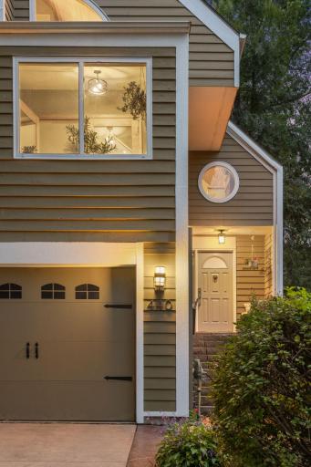 A welcoming entry is complemented by custom architectural elements, arched windows, warm lighting, and lush landscaping.