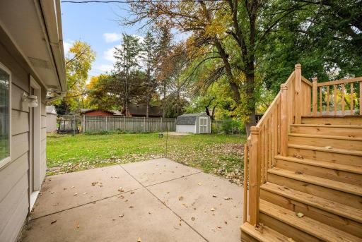 Brand-new deck overlooking a fully enclosed, 6-foot privacy-fenced backyard with a patio, storage shed, and two access gates.