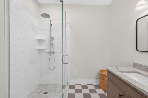 Upscale primary bath addition featuring a custom-tiled shower, classic checkerboard tile floor, and new vanity.
