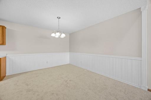 The kitchen flows seamlessly into the dining room, highlighted by wainscoting, new carpeting, and a classic chandelier.