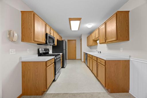 The kitchen features ample wood cabinetry, new stainless steel appliances, a pantry, and plenty of additional storage.