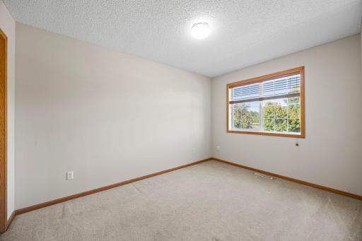 Bedroom Two is located next to the primary bedroom and features carpeting, ample closet space, and a front-facing window.
