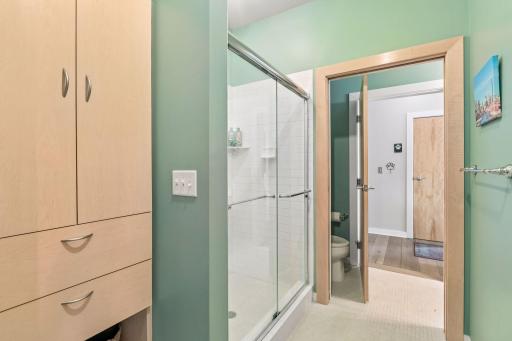 This en-suite bathroom features a glass-enclosed walk-in shower with subway tile, built-in cabinetry, and generous storage.