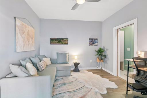 The second bedroom is bright, versatile room featuring a comfortable sectional, contemporary lighting, and space for a home office or additional living area.