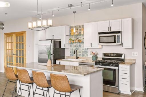The kitchen is a chef's delight featuring a large center island with ample cabinetry, stone countertops, and modern hardware.