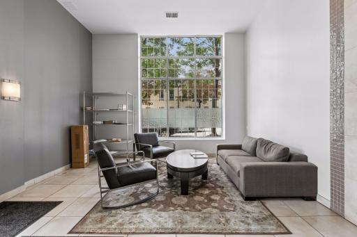 Inviting condo lobby with a comfortable seating area, oversized windows, and abundant natural light, creating a bright and welcoming entrance.