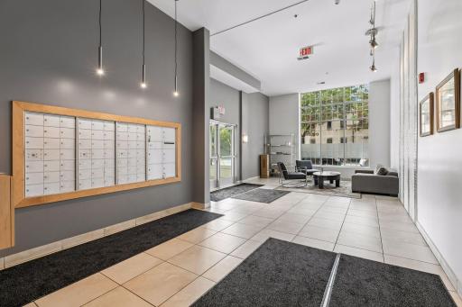 The spacious, contemporary lobby features tiled floors, modern pendant lighting, secure mailboxes, and a generous seating area overlooking the landscaped courtyard.