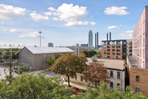 Elevated view showcasing the surrounding Minneapolis neighborhood, nearby architecture, mature trees, and open blue skies.