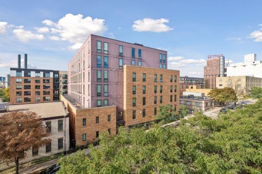 Elevated view showcasing the surrounding Minneapolis neighborhood, nearby architecture, mature trees, and open blue skies.