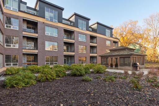 Beautifully landscaped private courtyard with mature trees, established plantings, walking paths, and a charming screened gazebo.