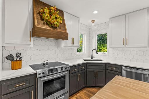The hood over the stove accentuates the butcher block center island.