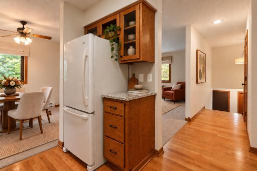 Oak hardwood flooring adds warmth to the main-level spaces, complemented by a convenient pantry closet near the kitchen and a half bath along the hallway. (Virtually staged photo.)